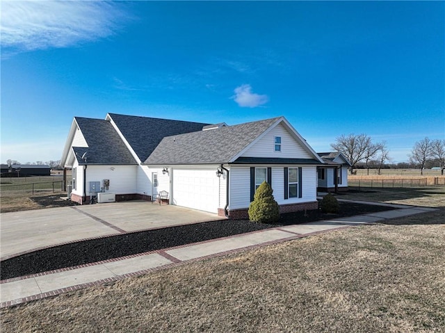 view of front facade featuring a front lawn, fence, roof with shingles, a garage, and driveway