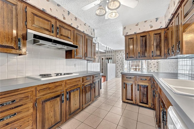 kitchen featuring under cabinet range hood, a textured ceiling, wallpapered walls, and ceiling fan