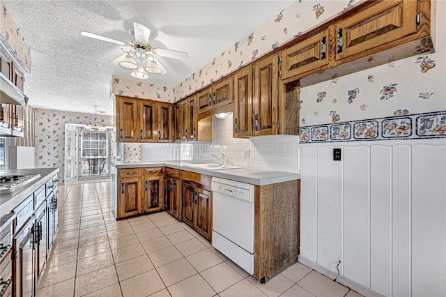 kitchen with a sink, a textured ceiling, wallpapered walls, dishwasher, and ceiling fan