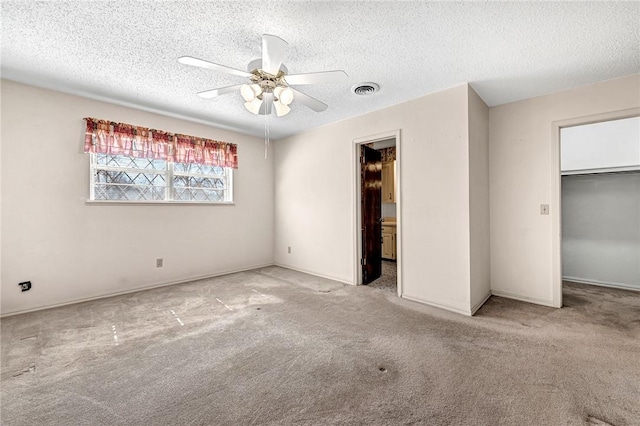 unfurnished bedroom featuring visible vents, a walk in closet, ceiling fan, carpet flooring, and a textured ceiling