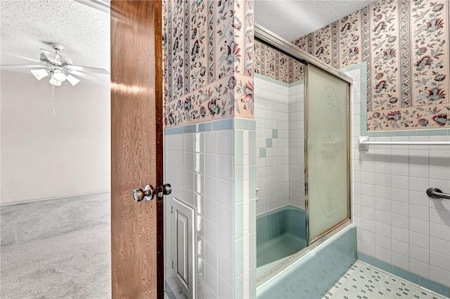 full bath featuring a wainscoted wall, wallpapered walls, an enclosed shower, a textured ceiling, and tile walls