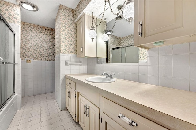 bathroom with a wainscoted wall, a textured ceiling, tile walls, wallpapered walls, and vanity