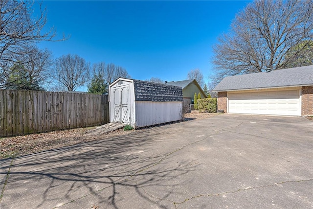 view of side of property with an outbuilding, fence, a garage, and driveway