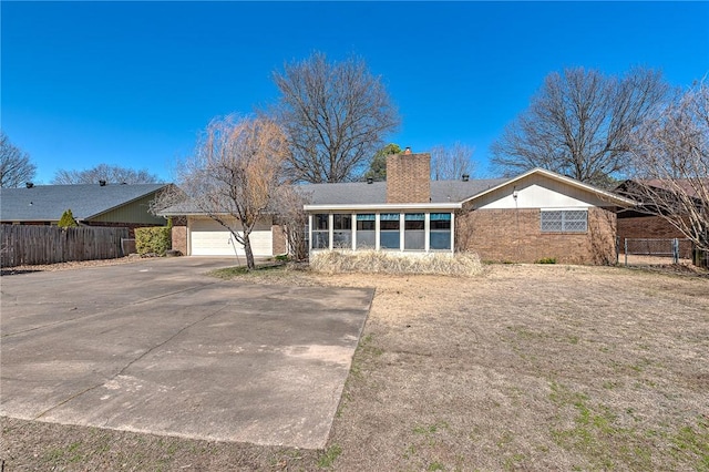 back of house featuring fence, brick siding, driveway, and a chimney