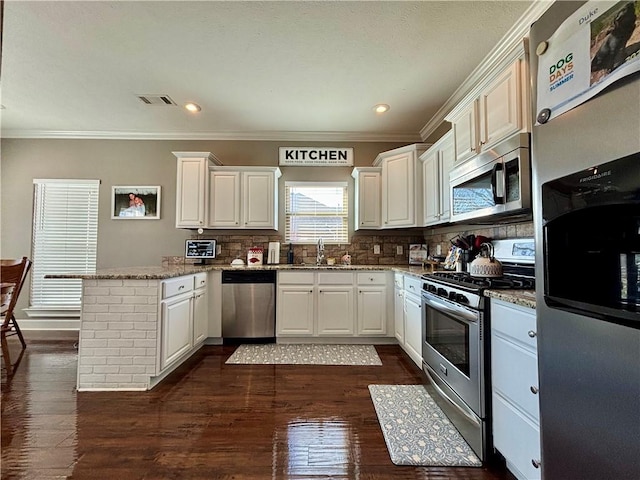 kitchen with visible vents, ornamental molding, appliances with stainless steel finishes, a peninsula, and dark wood-style flooring