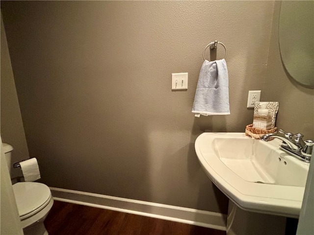 bathroom featuring a sink, baseboards, toilet, and wood finished floors