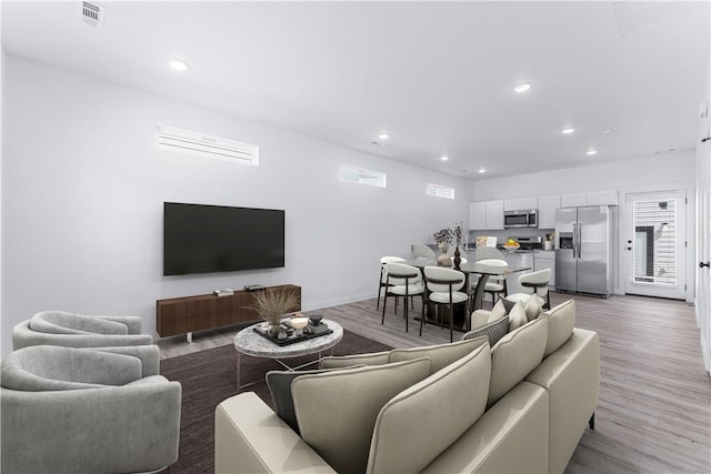 living area featuring recessed lighting, a healthy amount of sunlight, visible vents, and light wood finished floors