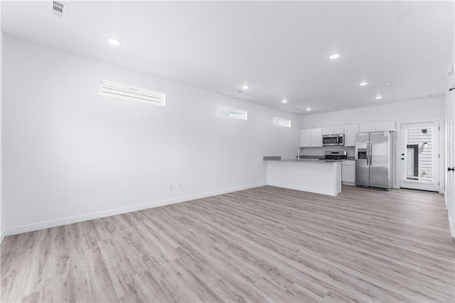 kitchen featuring open floor plan, light wood-style flooring, appliances with stainless steel finishes, and white cabinetry