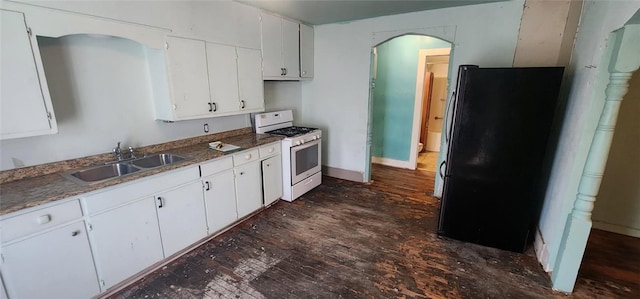 kitchen with white cabinets, white gas stove, freestanding refrigerator, and a sink