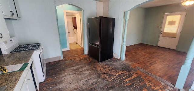 kitchen featuring dark wood-style floors, arched walkways, white gas stove, and freestanding refrigerator