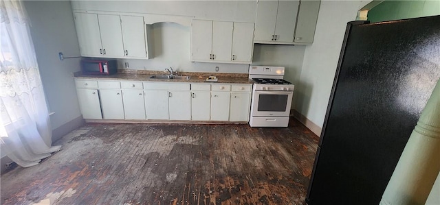 kitchen featuring gas range gas stove, dark wood finished floors, freestanding refrigerator, white cabinets, and a sink