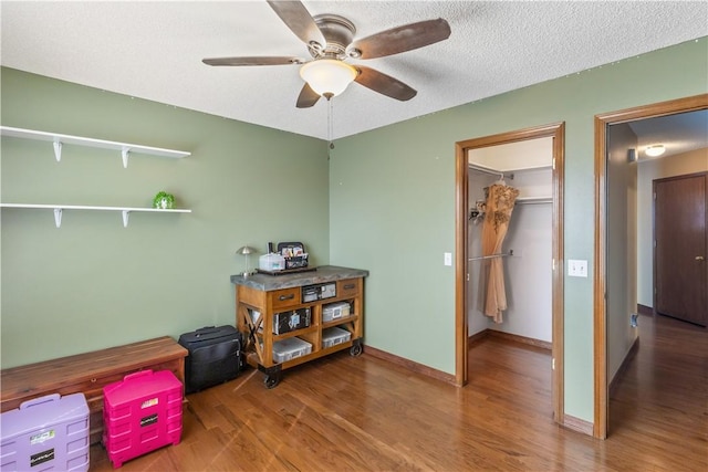 interior space featuring a textured ceiling, wood finished floors, baseboards, and ceiling fan