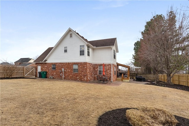 back of house with a patio area, a lawn, brick siding, and a fenced backyard