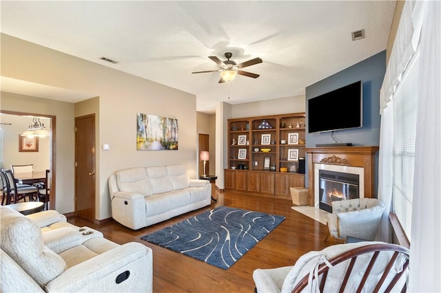 living room with visible vents, wood finished floors, ceiling fan, and a premium fireplace