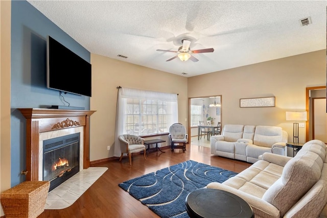 living area with wood finished floors, a ceiling fan, visible vents, and a tile fireplace