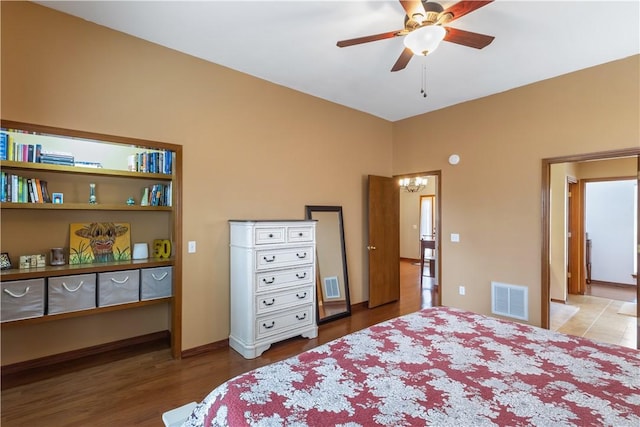 bedroom with visible vents, wood finished floors, and ceiling fan with notable chandelier