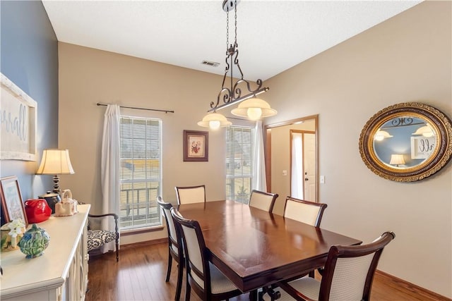 dining room with dark wood-style floors, visible vents, and baseboards