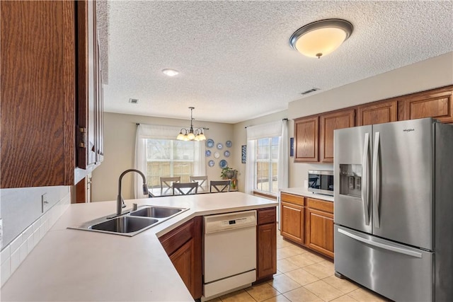 kitchen with a sink, stainless steel appliances, a peninsula, light countertops, and a chandelier