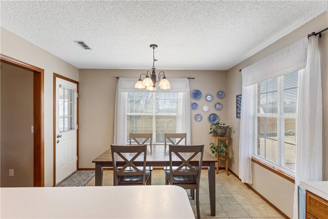 dining area with light tile patterned floors, visible vents, a textured ceiling, and an inviting chandelier