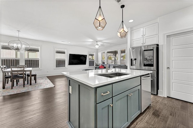 kitchen featuring a sink, light countertops, ceiling fan with notable chandelier, stainless steel appliances, and dark wood-style flooring