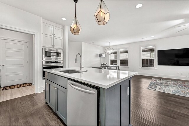 kitchen with dark wood-style floors, gray cabinets, a sink, stainless steel appliances, and light countertops