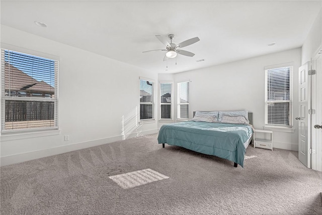 carpeted bedroom with visible vents, baseboards, and a ceiling fan