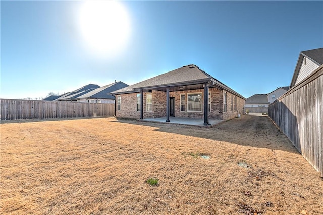 back of house with a patio area, brick siding, a fenced backyard, and a lawn