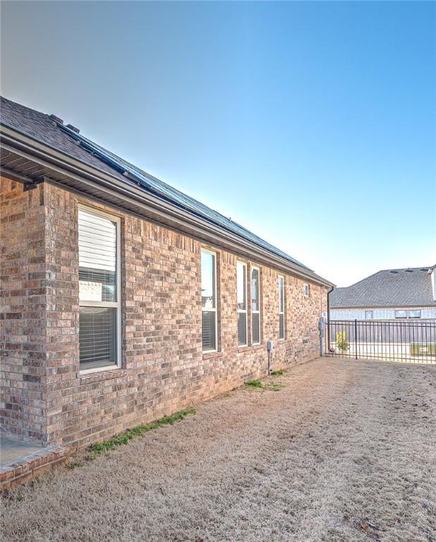 view of property exterior with brick siding and fence