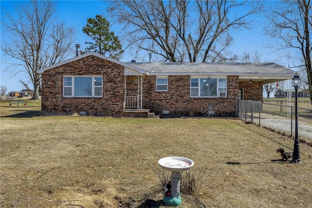 ranch-style house featuring brick siding, an attached carport, a front lawn, and fence