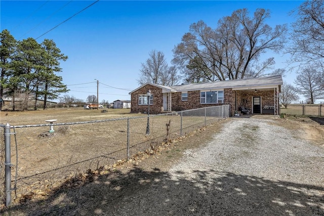 view of front of property with brick siding, a fenced front yard, a carport, and driveway