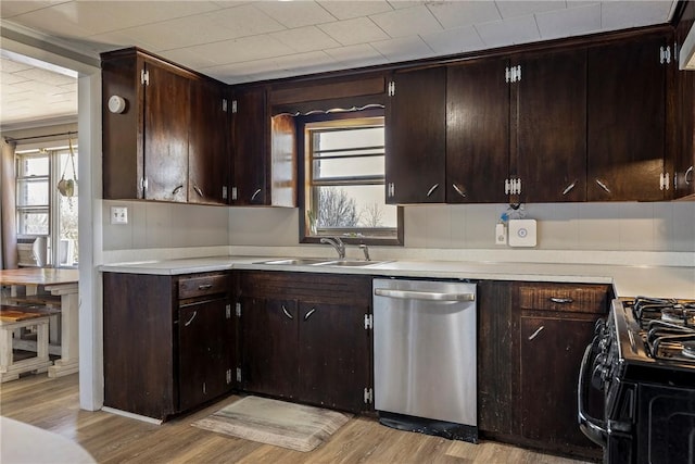 kitchen with a sink, light wood-style floors, stainless steel dishwasher, and black gas stove