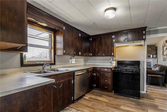 kitchen with wood finished floors, black gas stove, a sink, dark brown cabinets, and stainless steel dishwasher