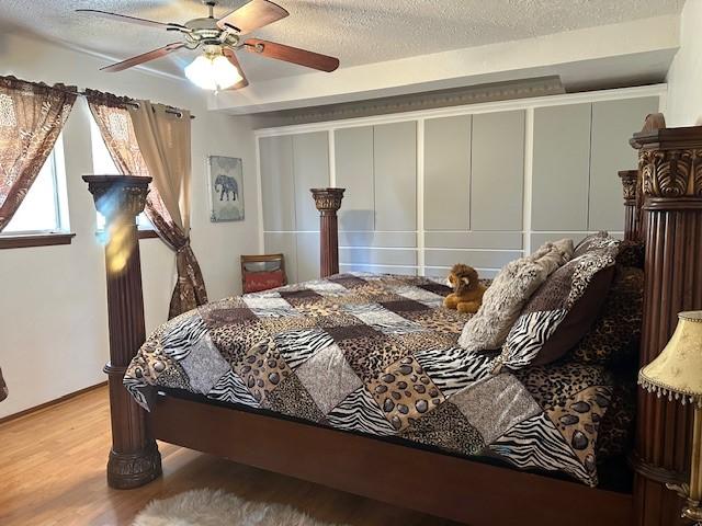 bedroom with ceiling fan, a textured ceiling, and wood finished floors