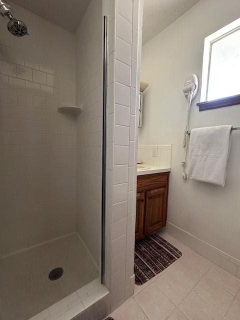 full bathroom featuring tile patterned floors, a stall shower, a textured ceiling, baseboards, and vanity