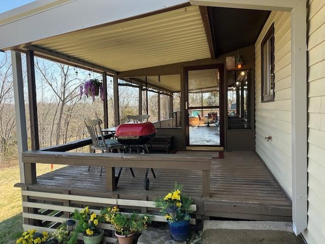 wooden deck with a grill and a sunroom