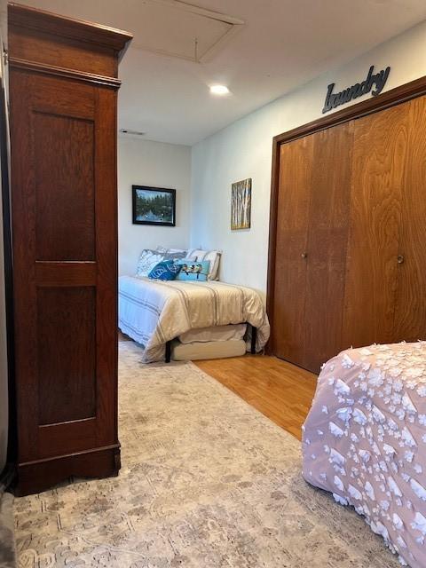 bedroom featuring a closet, attic access, and wood finished floors