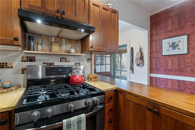 kitchen featuring ornamental molding, under cabinet range hood, backsplash, brown cabinetry, and stainless steel range with gas stovetop