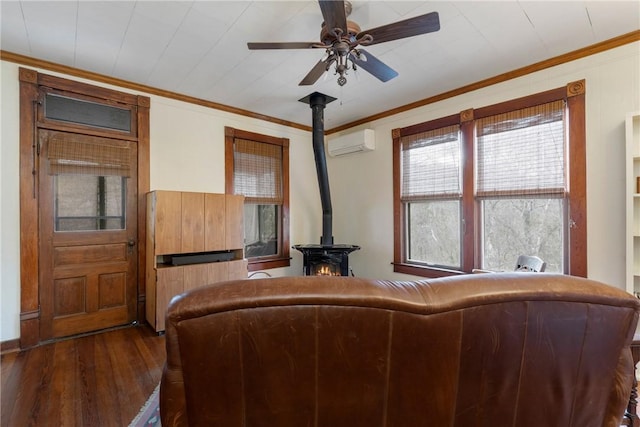 living room featuring an AC wall unit, a ceiling fan, wood finished floors, crown molding, and a wood stove