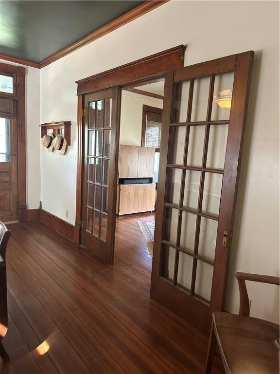 foyer entrance featuring radiator heating unit, crown molding, baseboards, and hardwood / wood-style flooring