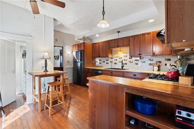 kitchen with a sink, wood counters, freestanding refrigerator, wood-type flooring, and decorative backsplash