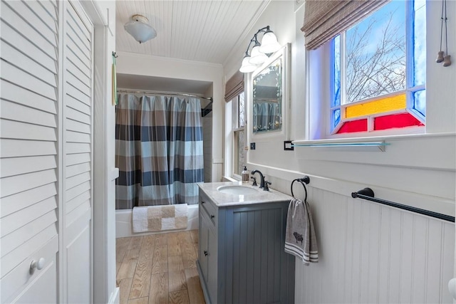 bathroom featuring a healthy amount of sunlight, crown molding, wainscoting, wood finished floors, and vanity