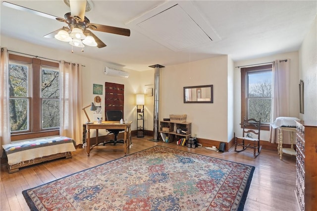 sitting room featuring baseboards, attic access, ceiling fan, an AC wall unit, and wood-type flooring