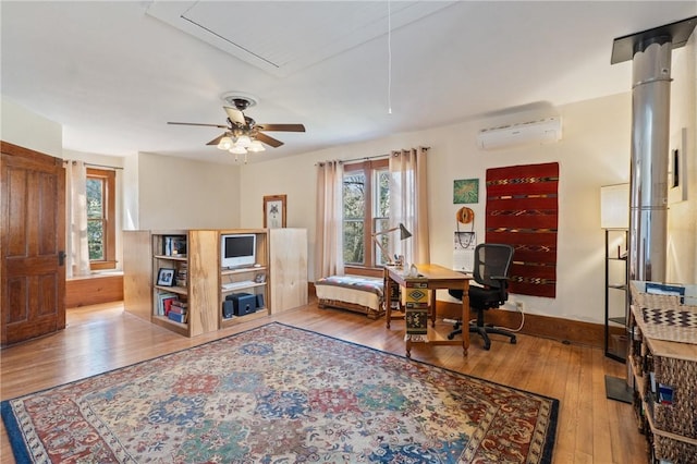 office featuring a wall mounted air conditioner, plenty of natural light, hardwood / wood-style floors, and ceiling fan