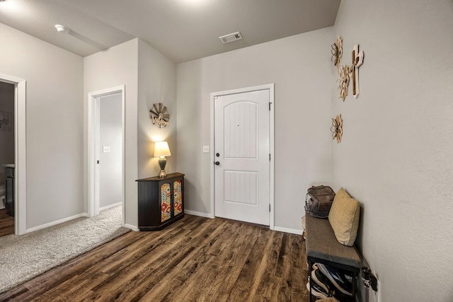 foyer with wood finished floors, visible vents, and baseboards