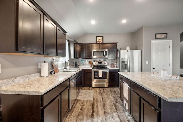 kitchen with a sink, stainless steel appliances, light wood-style floors, dark brown cabinetry, and light countertops