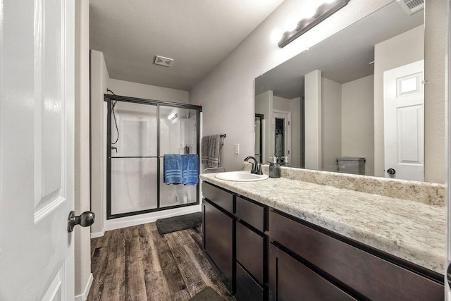 bathroom with vanity, visible vents, wood finished floors, and a stall shower