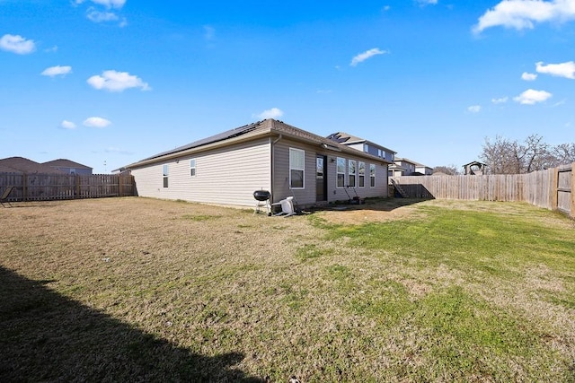 view of property exterior with solar panels, a lawn, and a fenced backyard