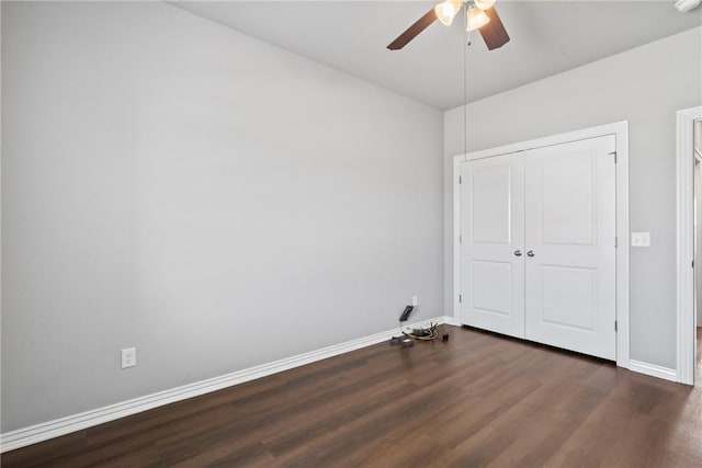 unfurnished bedroom with dark wood-style floors, baseboards, a closet, and ceiling fan