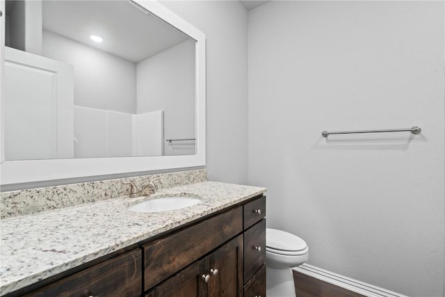 bathroom with vanity, toilet, wood finished floors, and baseboards