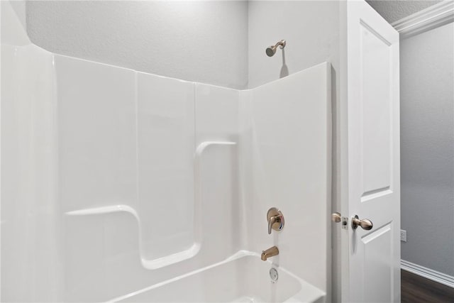 bathroom featuring bathing tub / shower combination, wood finished floors, and baseboards